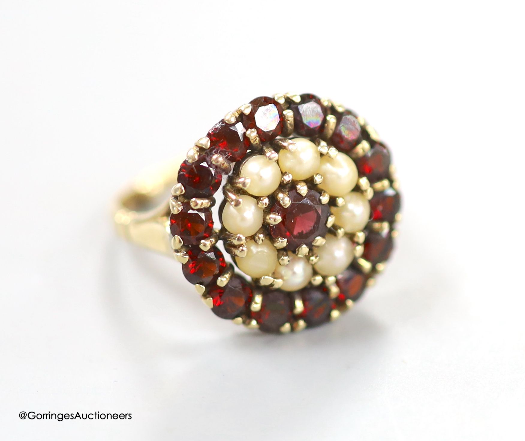 A modern 9ct gold, garnet and split pearl set circular cluster ring, size M, 5 grams.